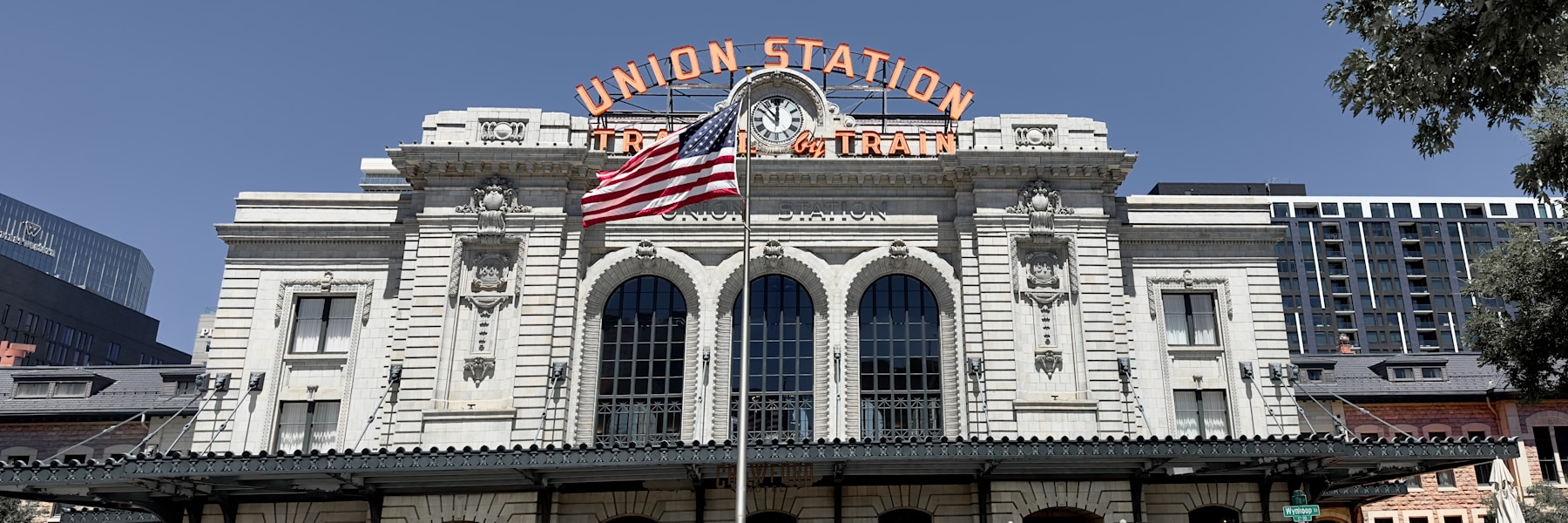 Denver Union Station’s historic facade and orange rooftop sign under a blue sky
